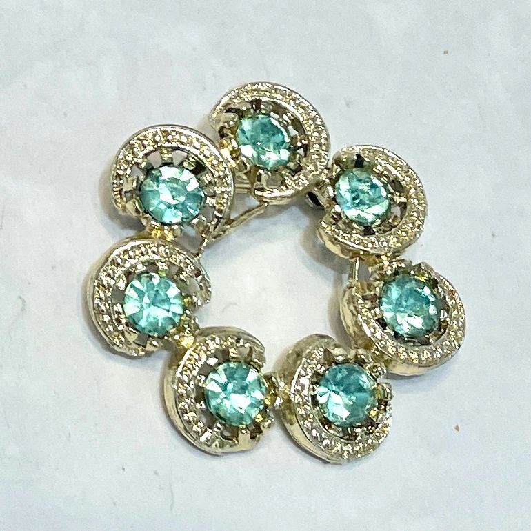 Gold circular brooch with aqua gemstones