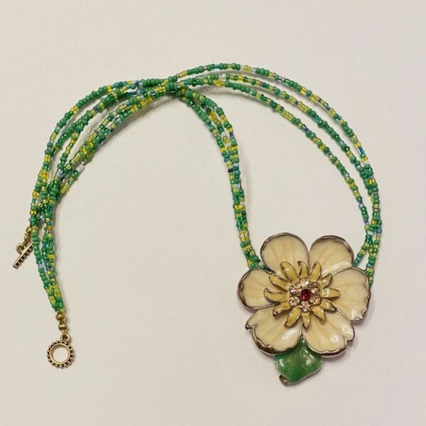 Green beaded necklace with cream flower pendant