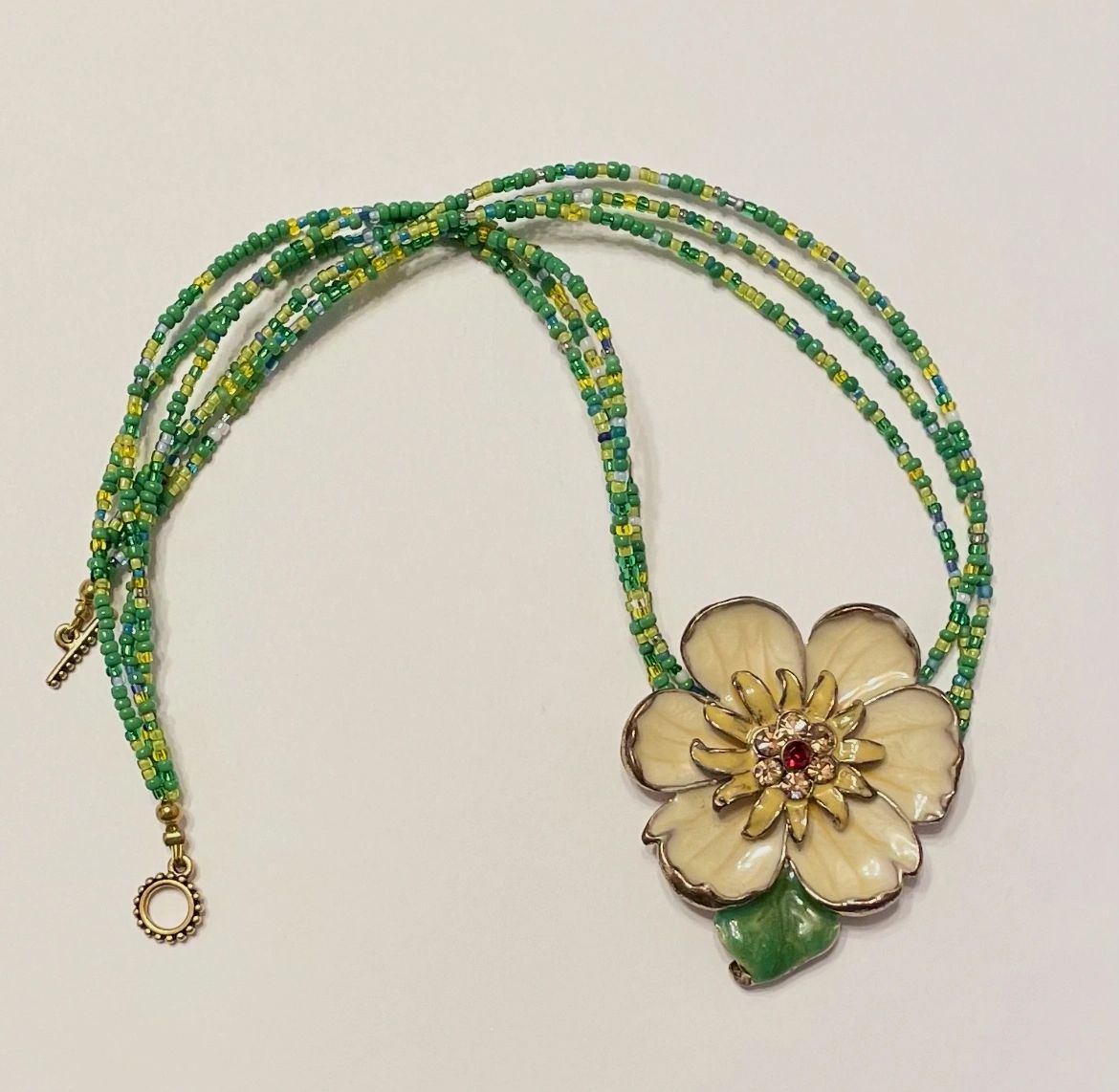 Green beaded necklace with cream flower pendant