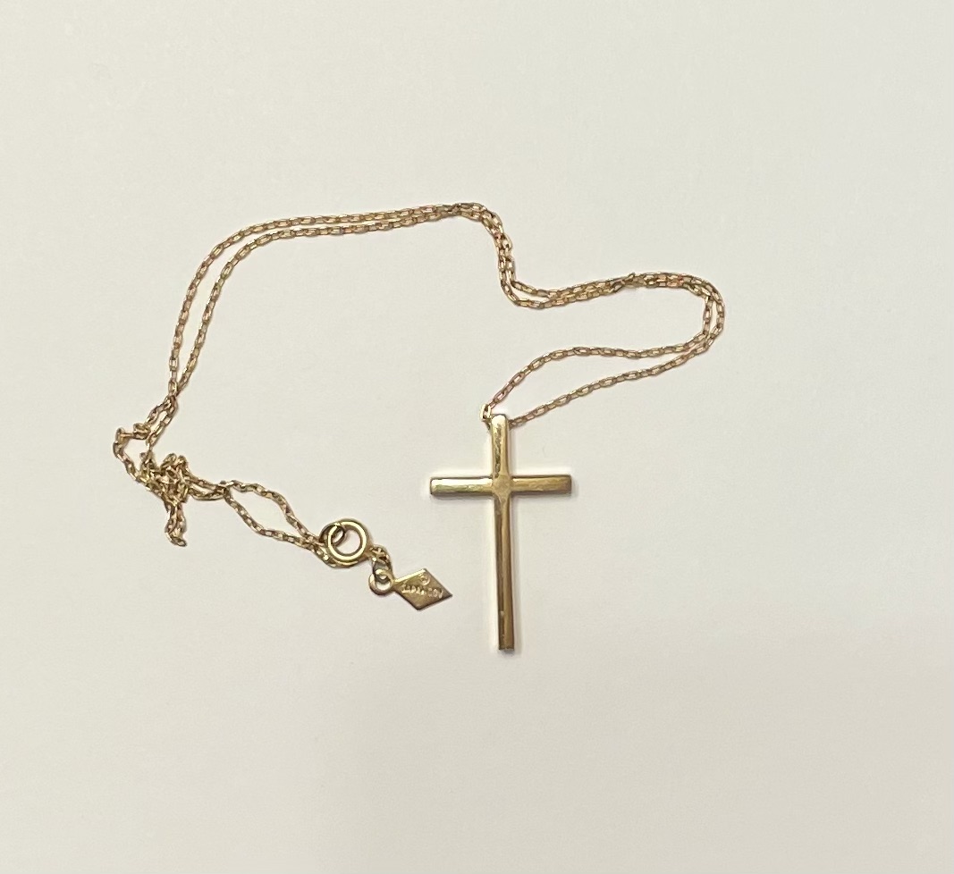 Simple gold cross necklace on white background