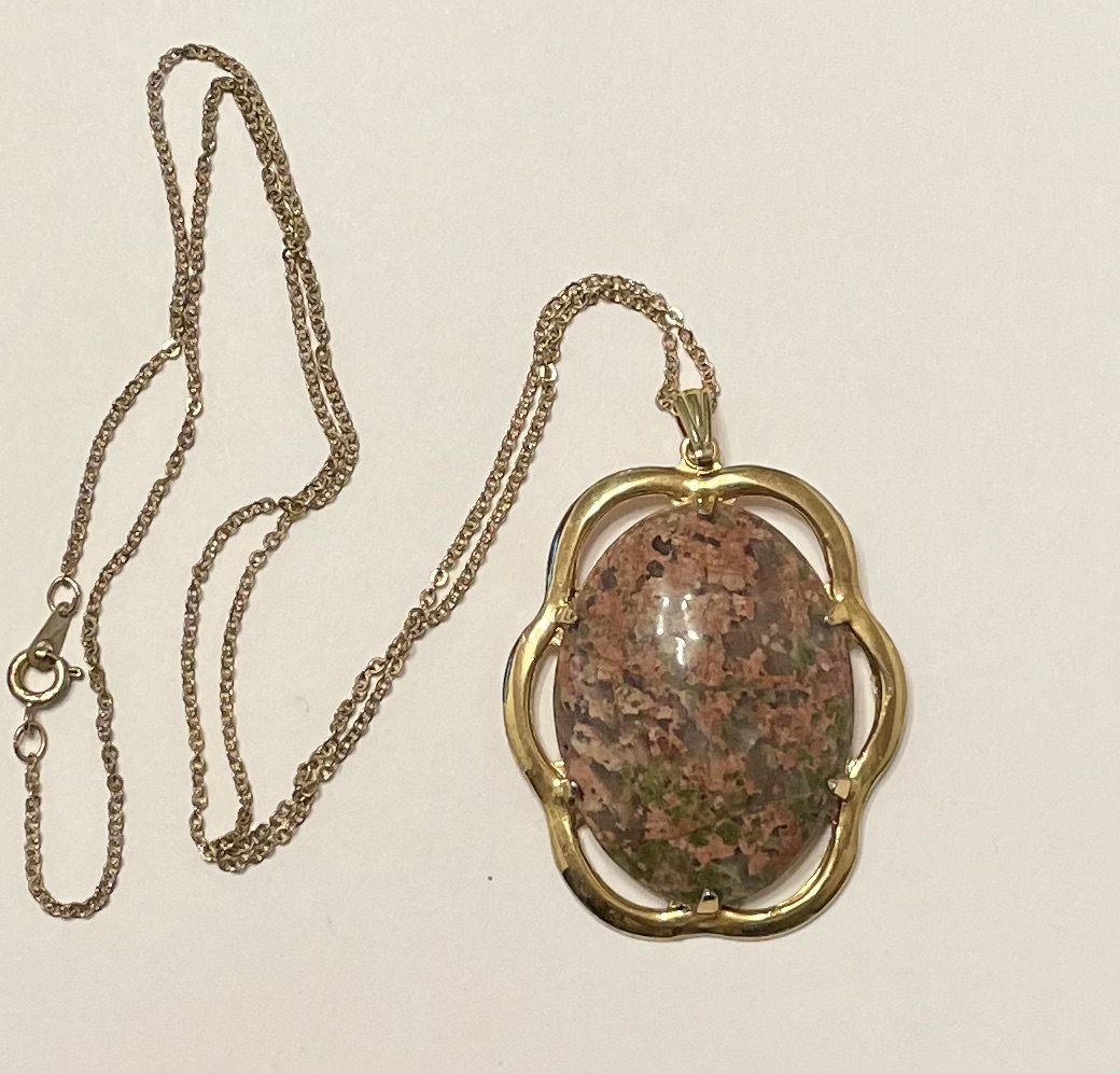 Gold pendant necklace with pink-speckled oval stone