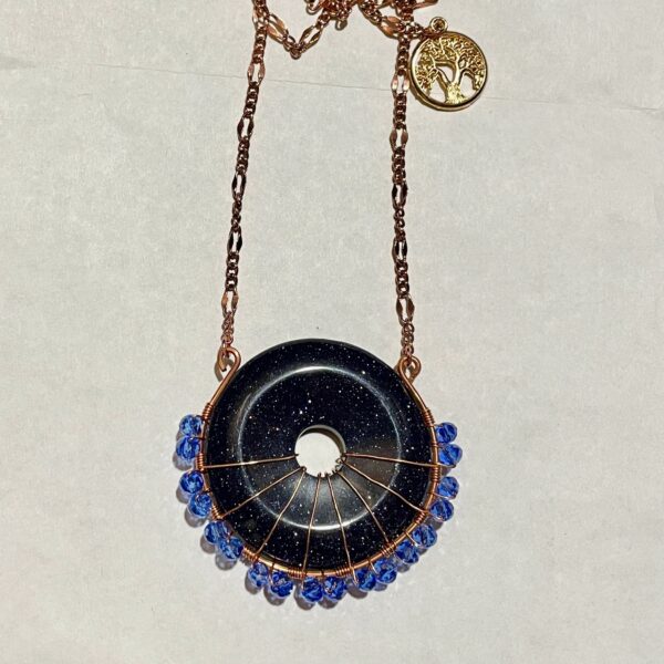 Black goldstone donut pendant with blue beads