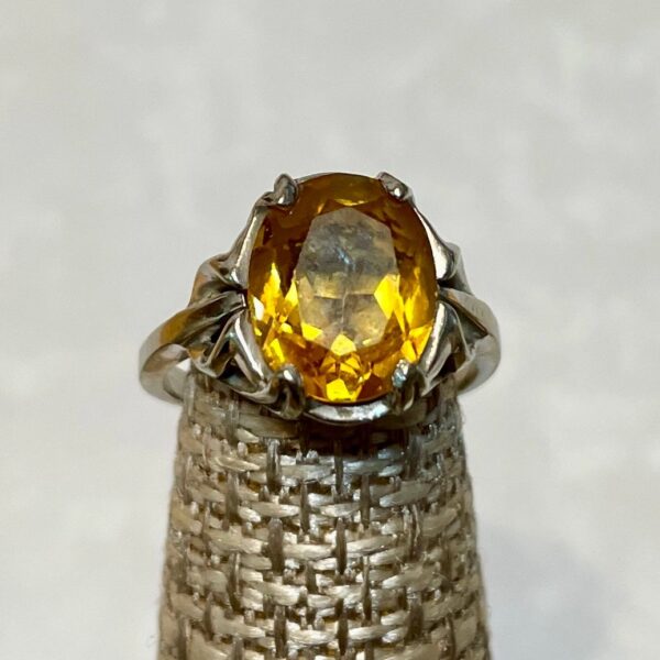 Oval yellow gemstone silver ring on beige stand