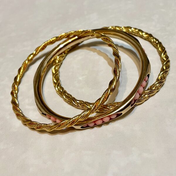Three gold twisted bangles with pink beads