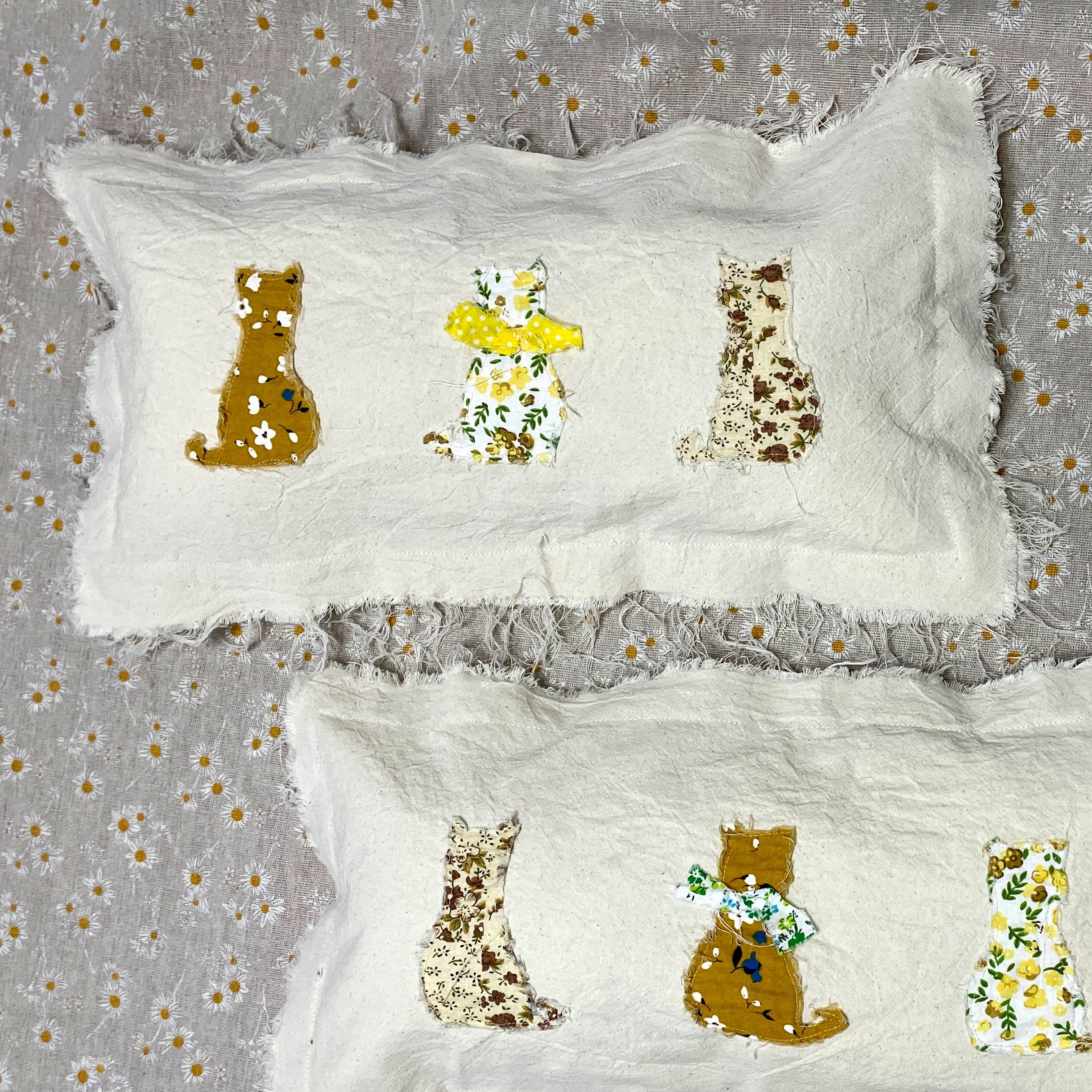 White pillows with three floral cat appliqués