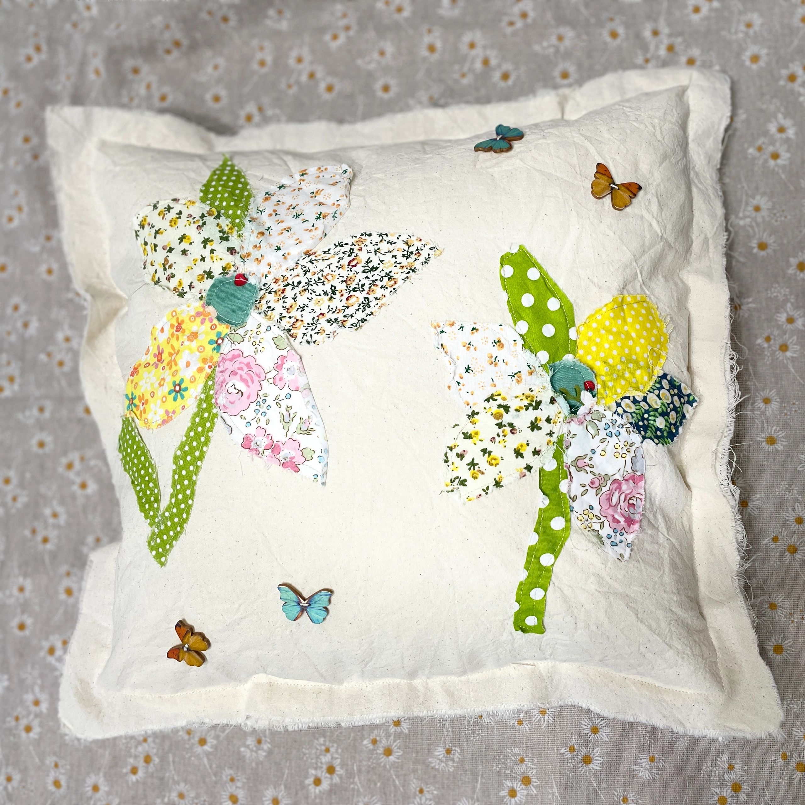 White pillow with floral fabric applique and butterflies