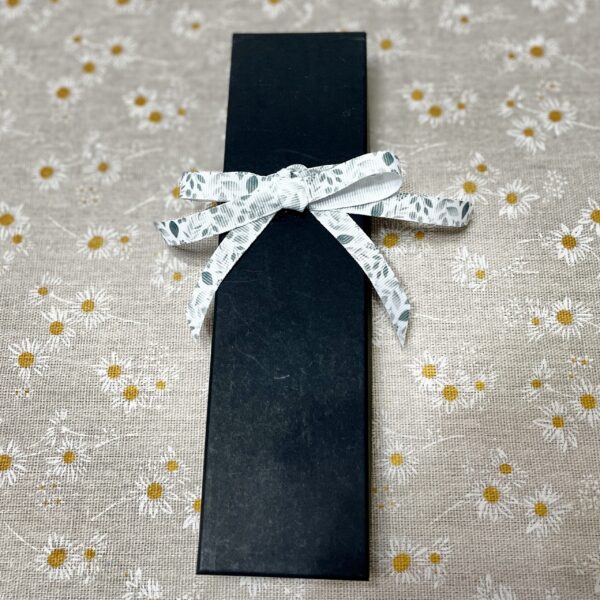 Black gift box with white floral ribbon bow