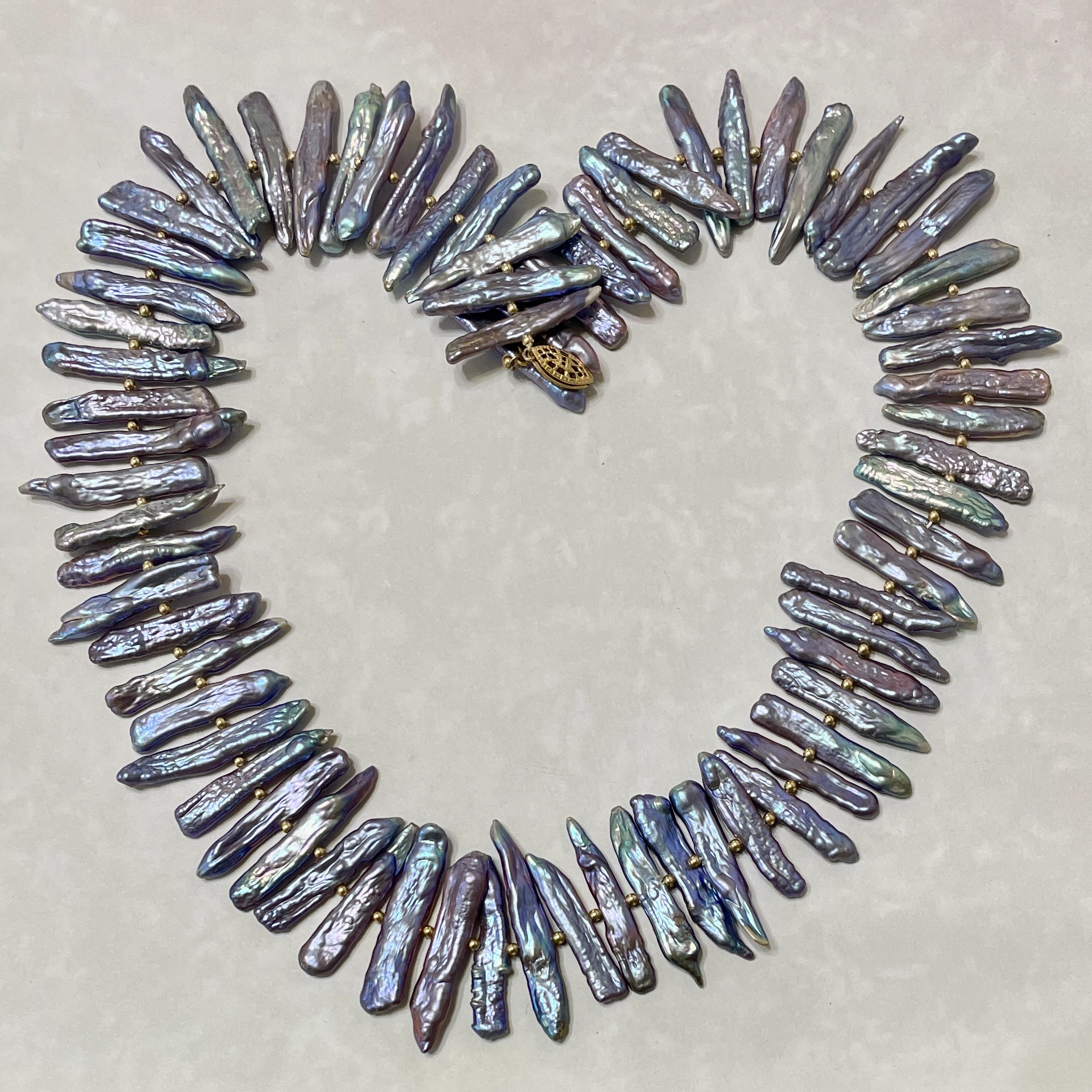 Iridescent elongated pearl necklace arranged in heart shape