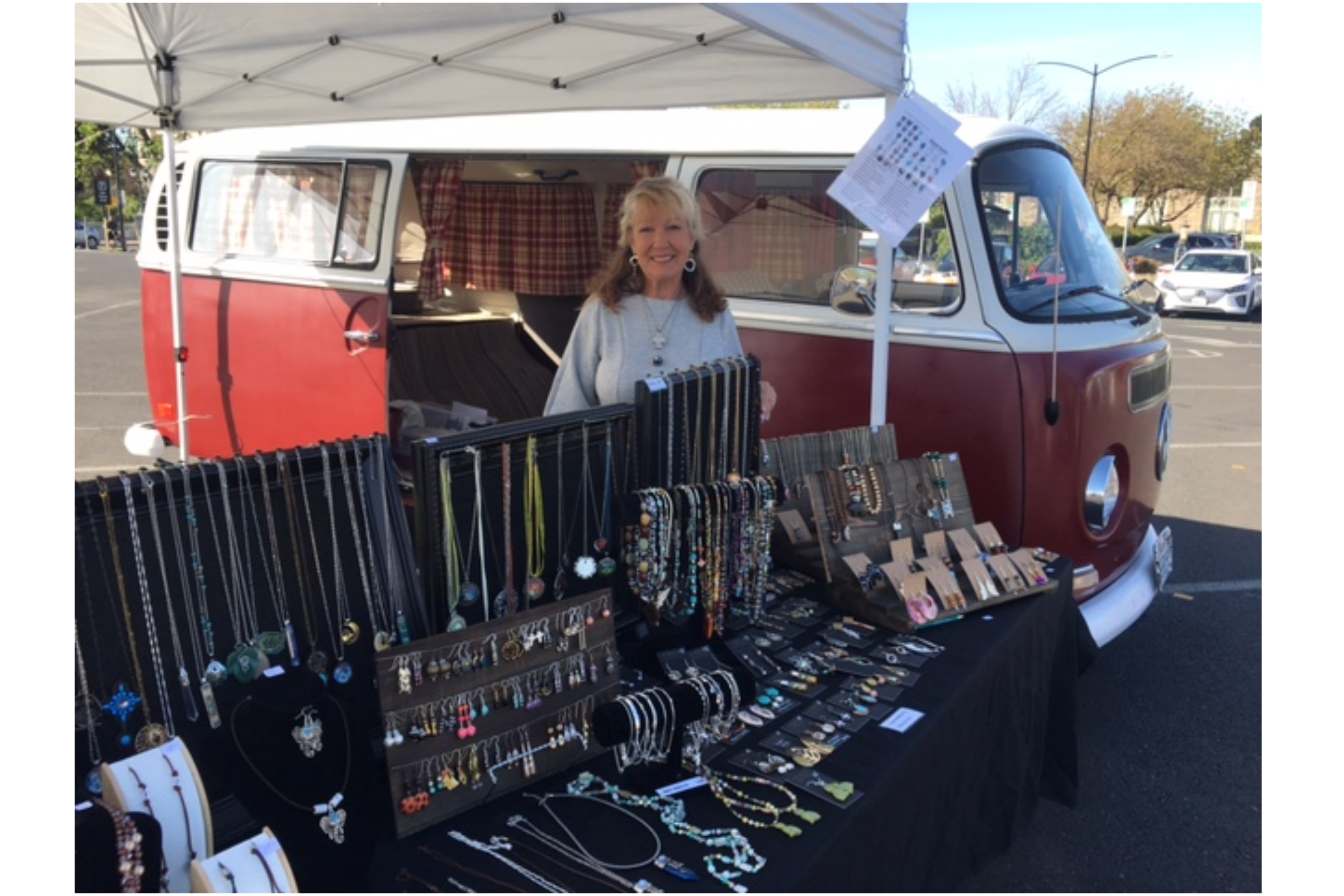 Woman selling jewelry beside red vintage van