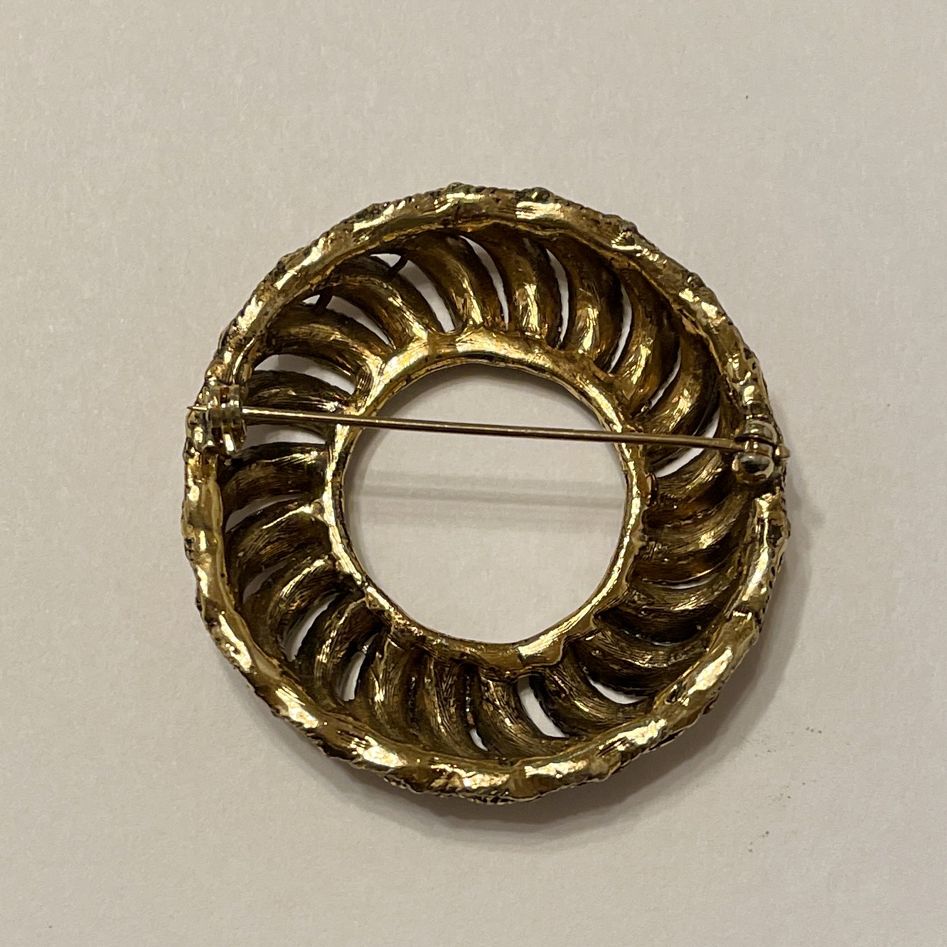 Vintage gold brooch with intricate circular design.