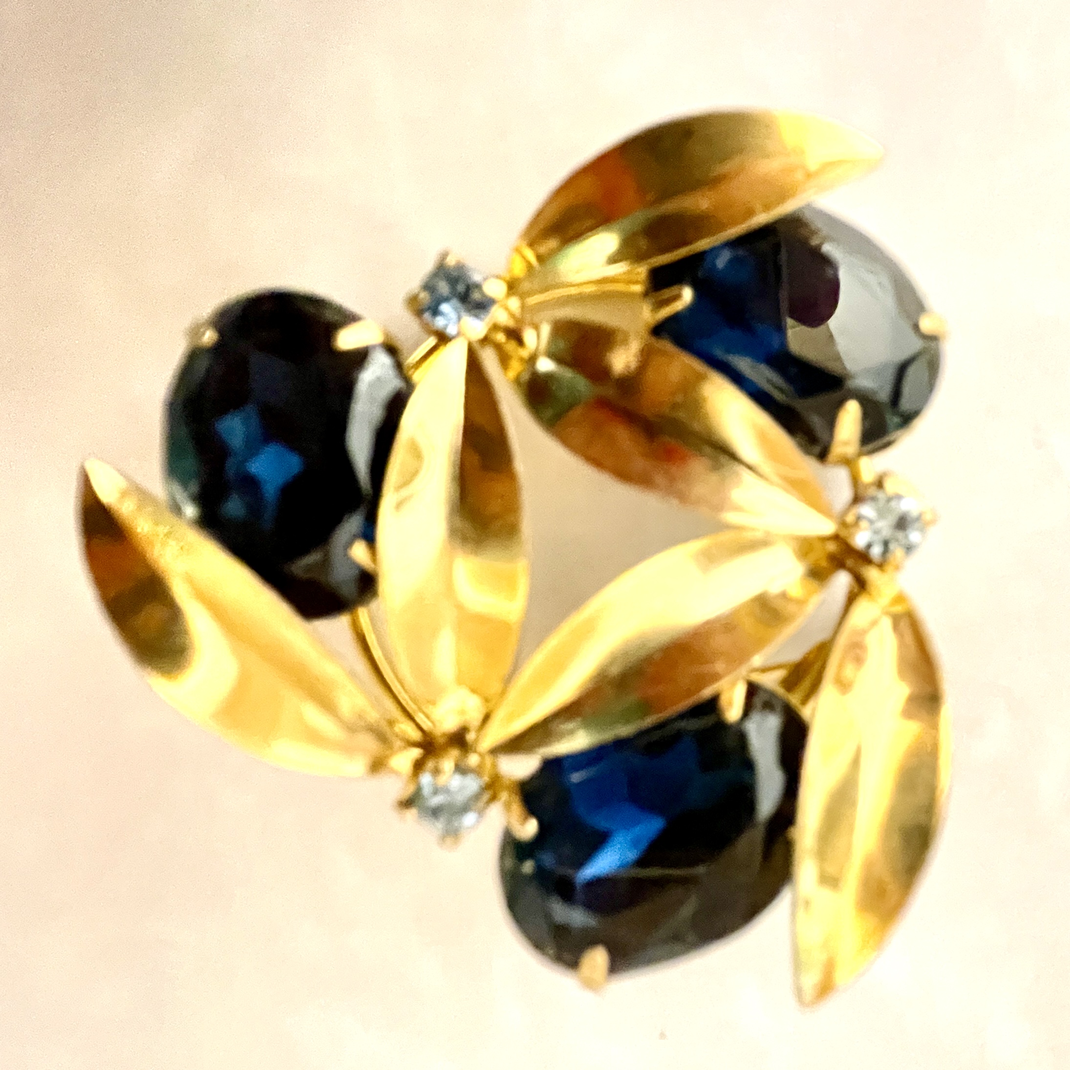 Gold brooch with dark blue gemstones and leaves.