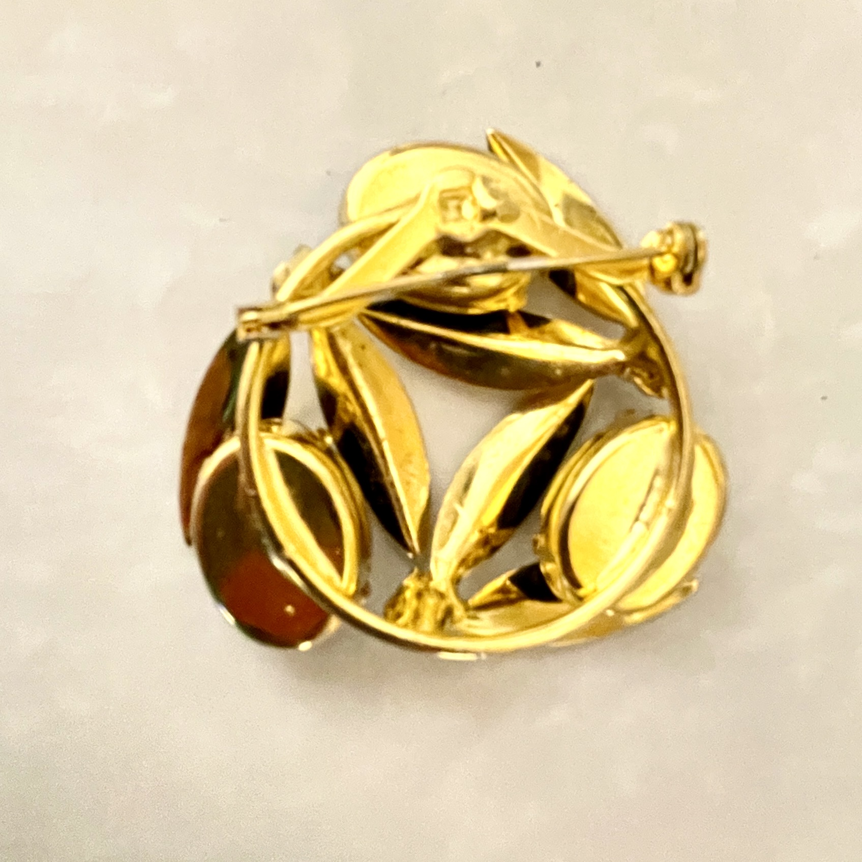 Gold brooch with leaf design and details.