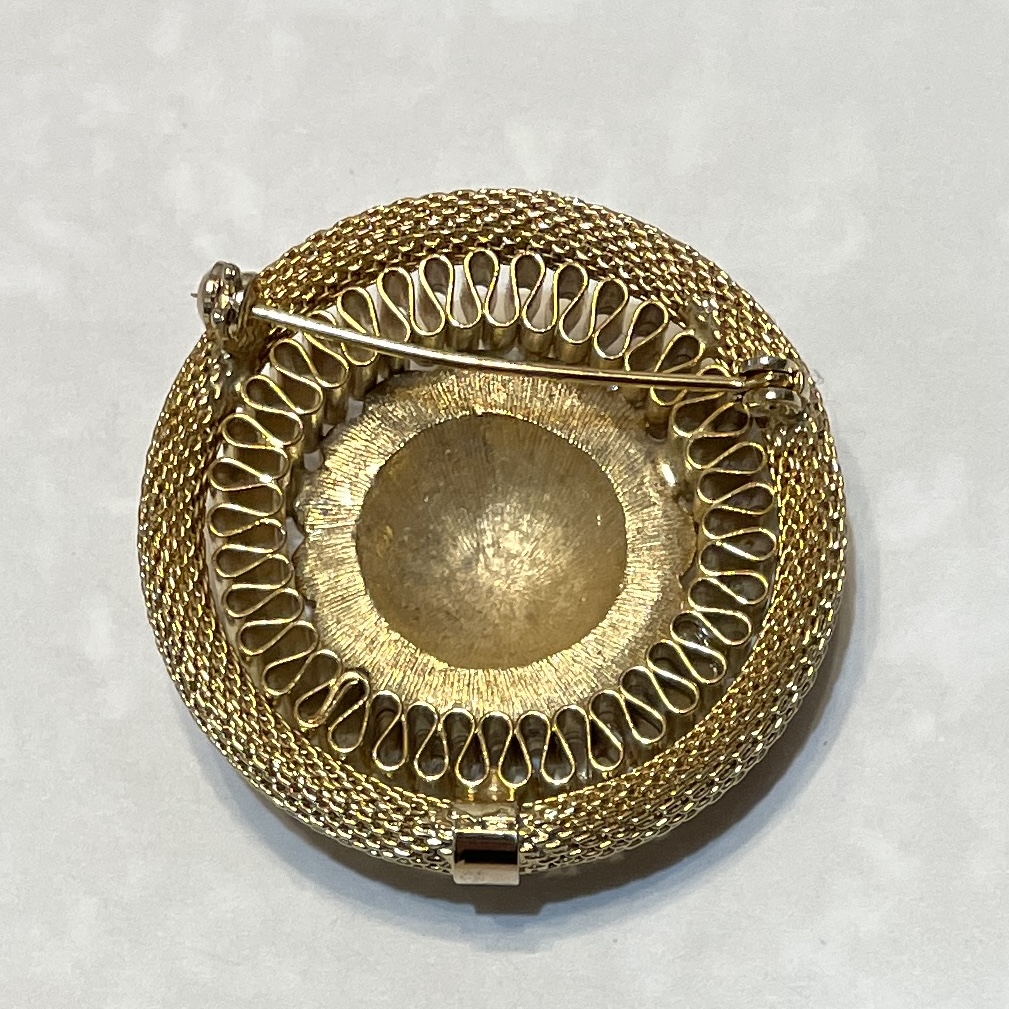 Intricate gold brooch with textured design.