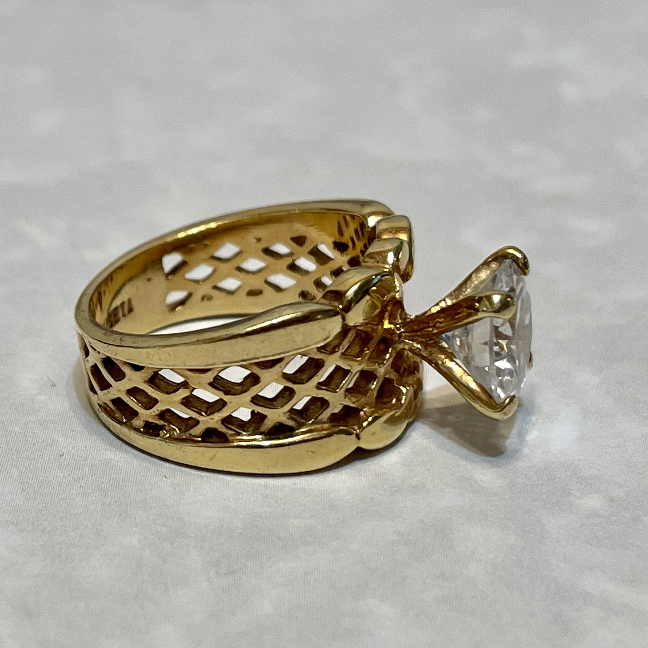 Gold ring with intricate lattice design and gemstone.