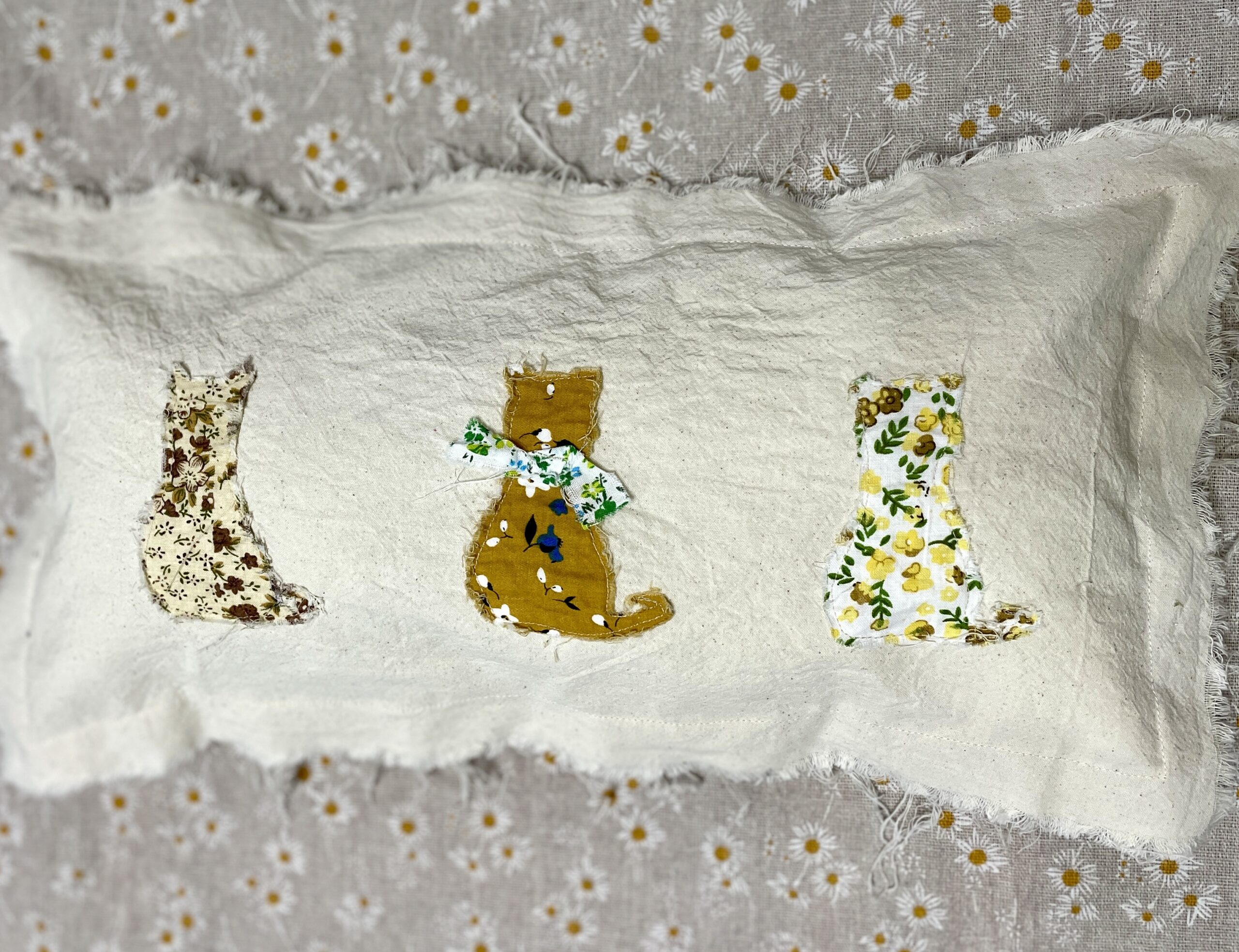 Three patterned fabric cat cutouts on cloth