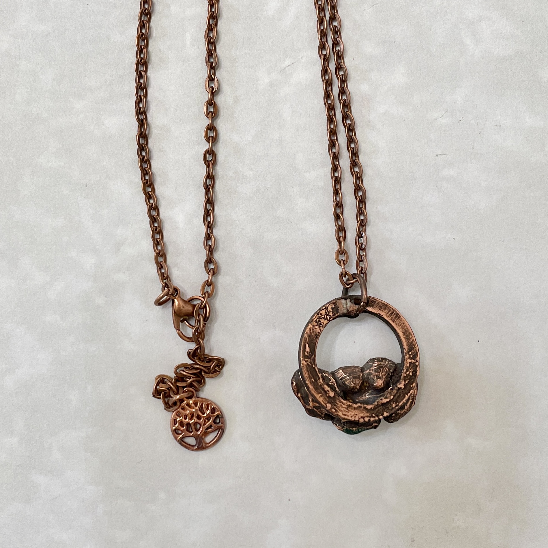 Two copper pendant necklaces on marble background