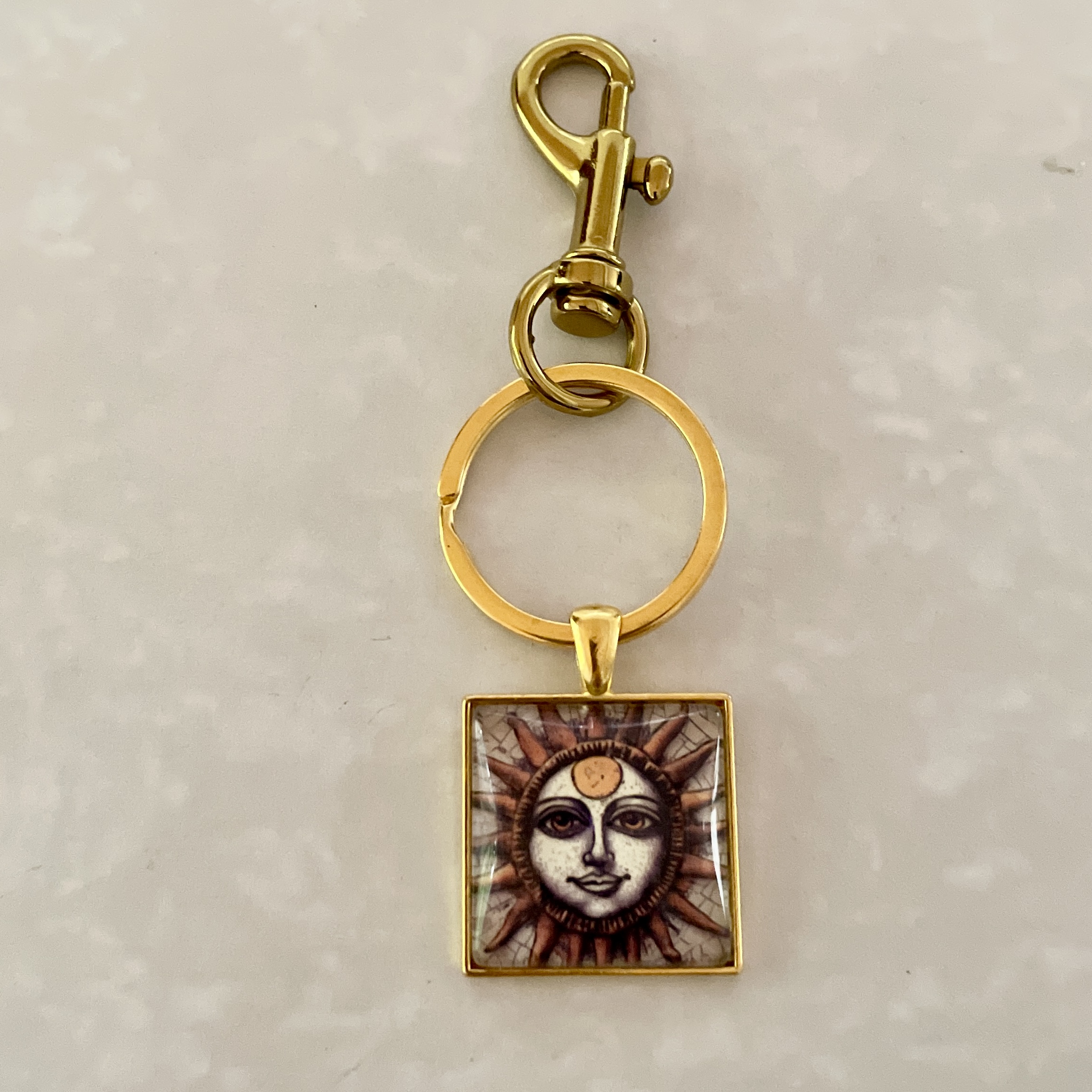 Gold keychain with sun design pendant.