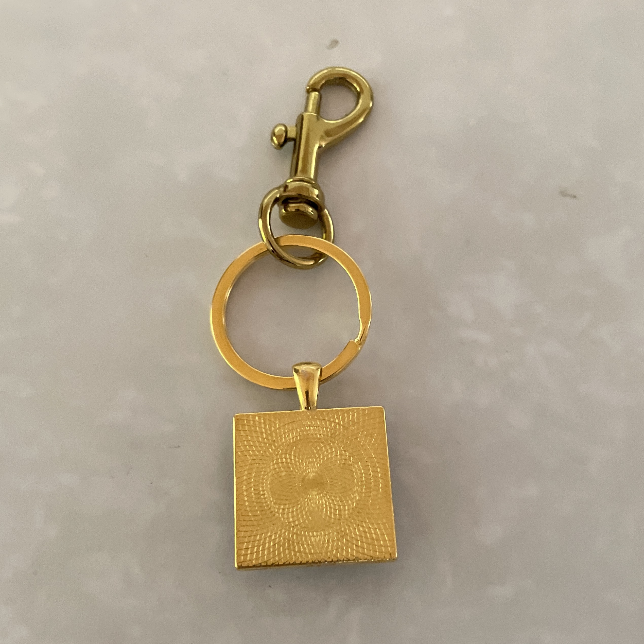 Gold square pendant with textured design.