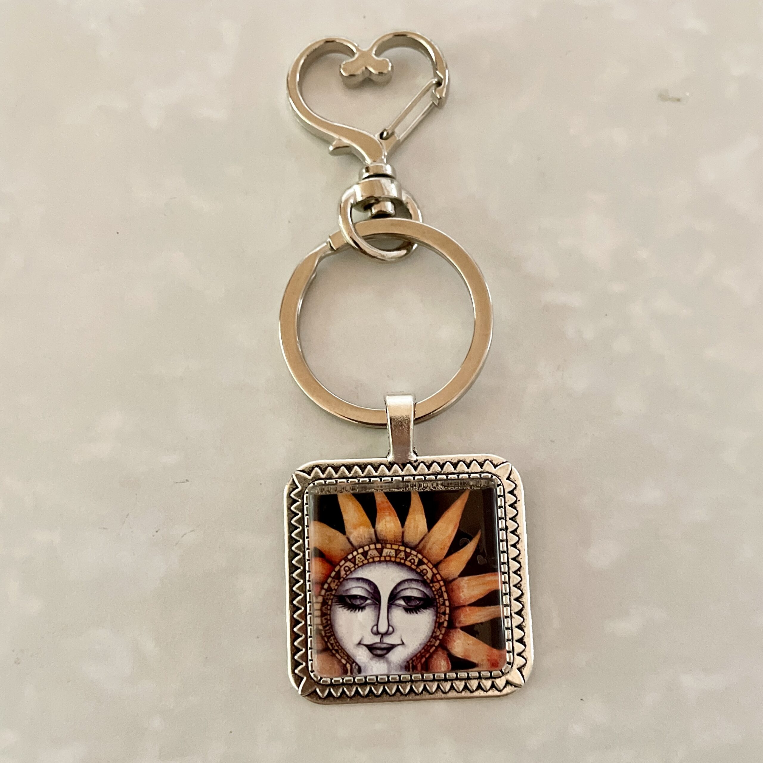 Silver keychain with sun face pendant