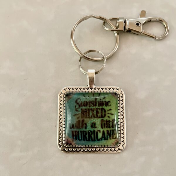 Square keychain reading "Sunshine mixed with hurricane