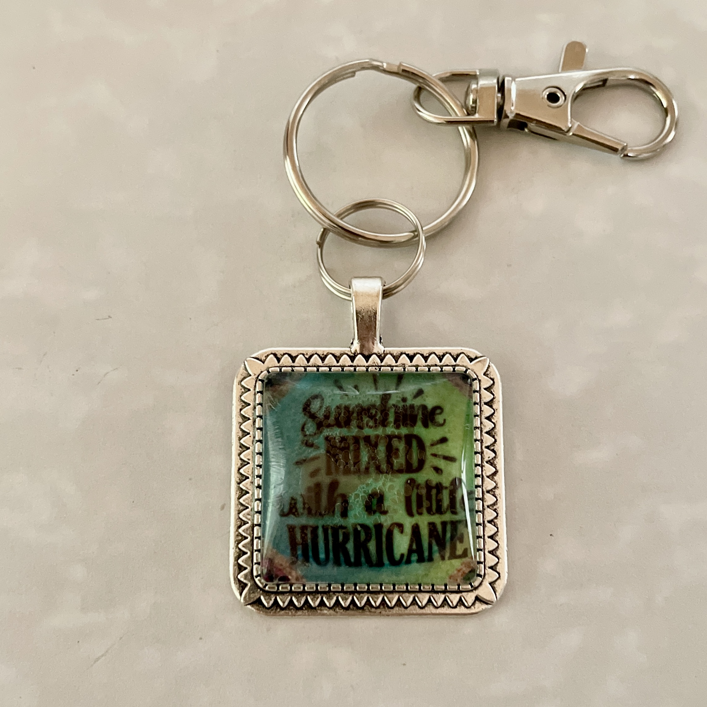 Square keychain reading "Sunshine mixed with hurricane