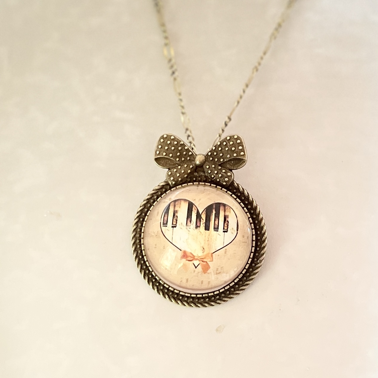 Bow necklace pendant with piano-key heart