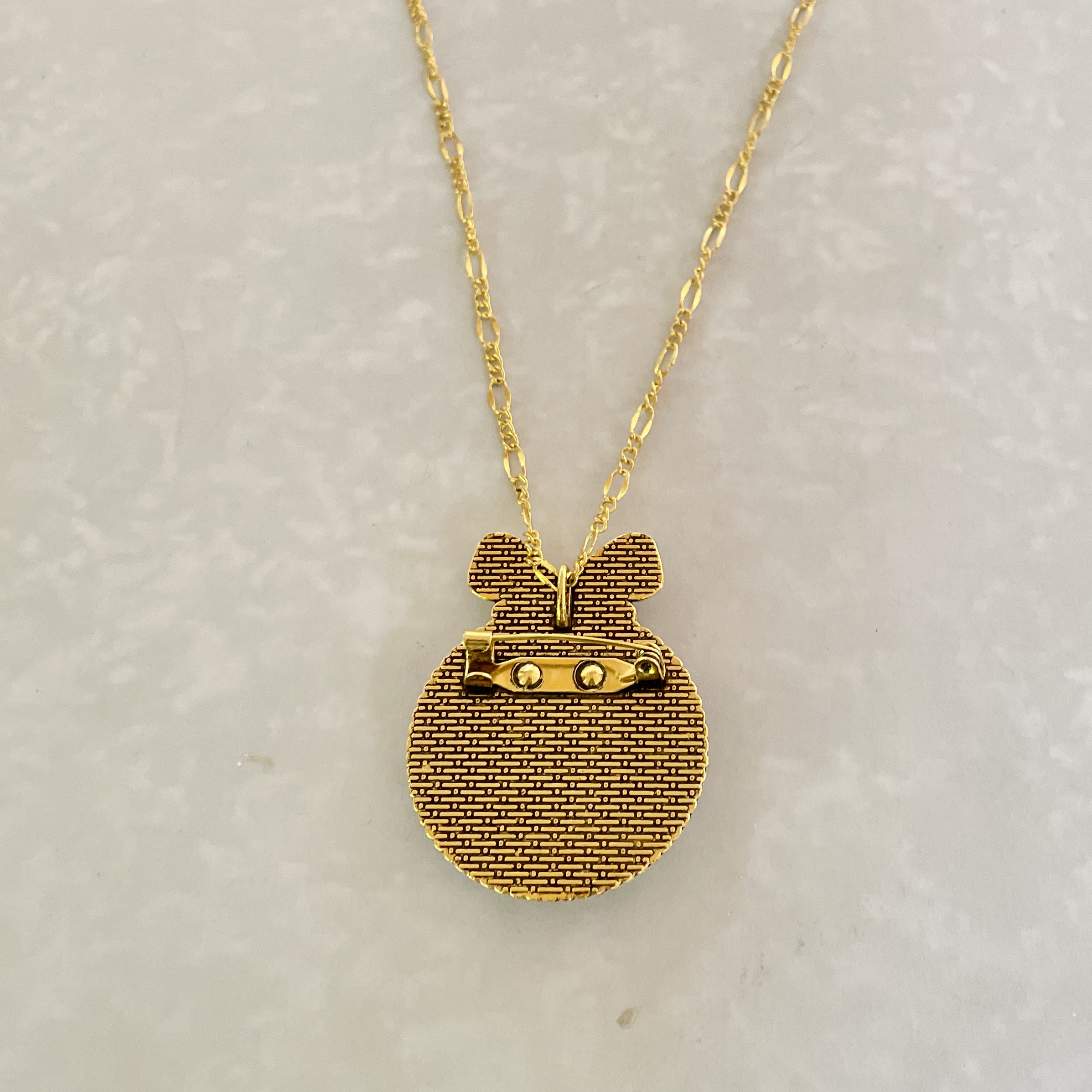 Gold textured circular pendant on chain
