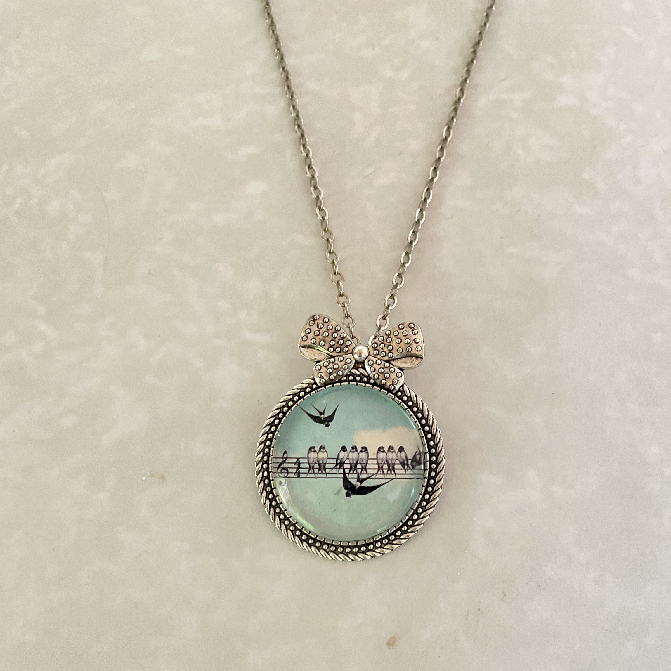Round silver bird pendant necklace with bow