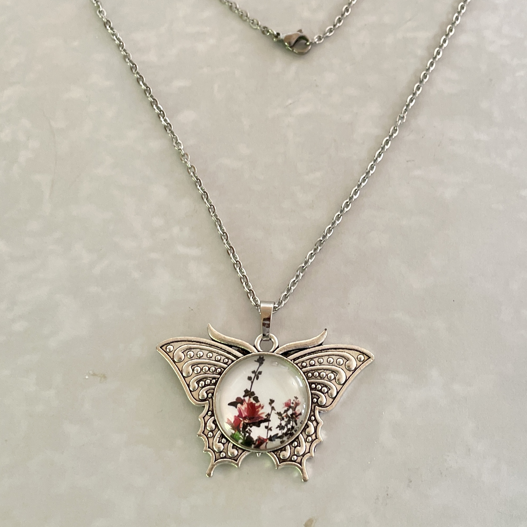 Silver butterfly pendant necklace with floral cabochon