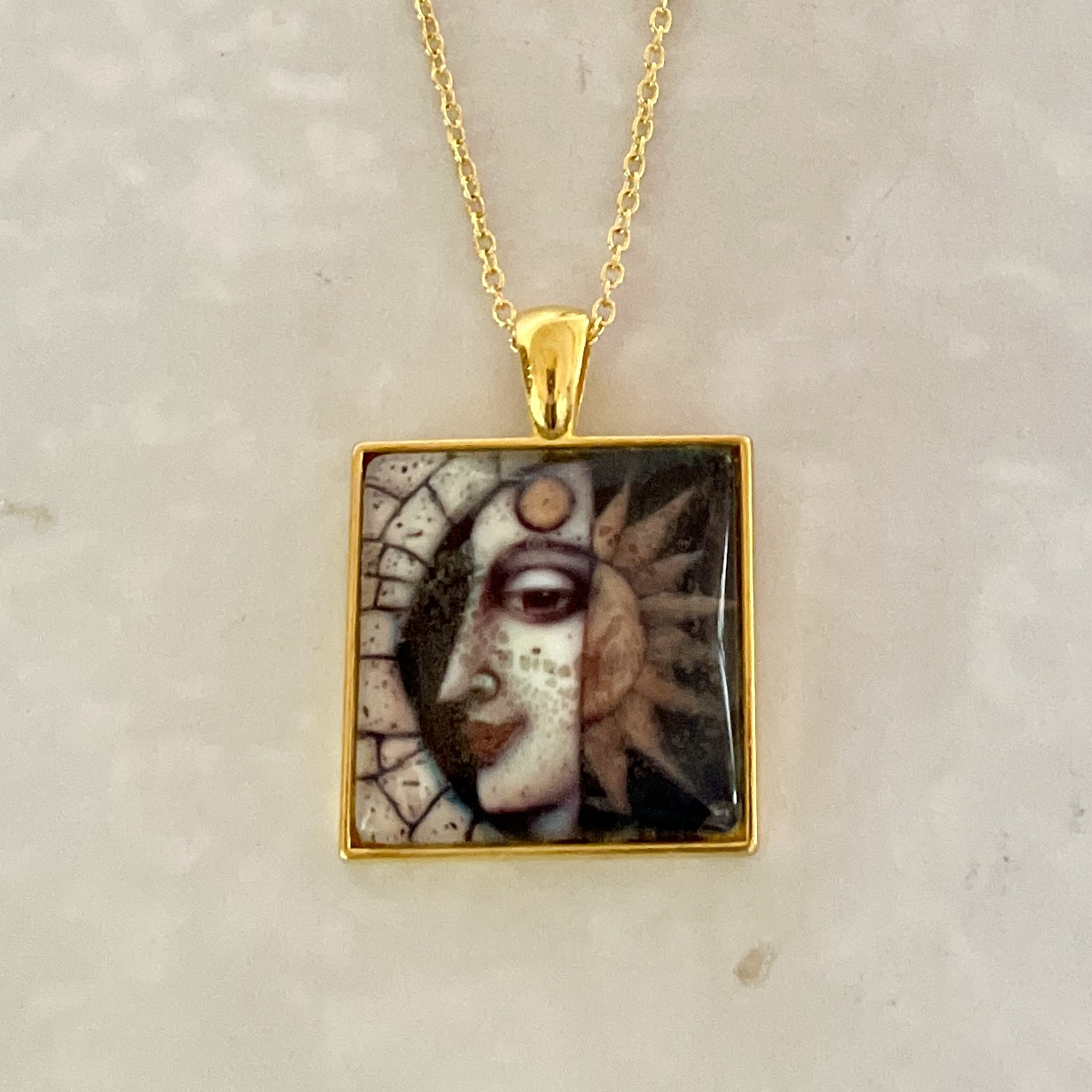 Gold square pendant with sun and moon face