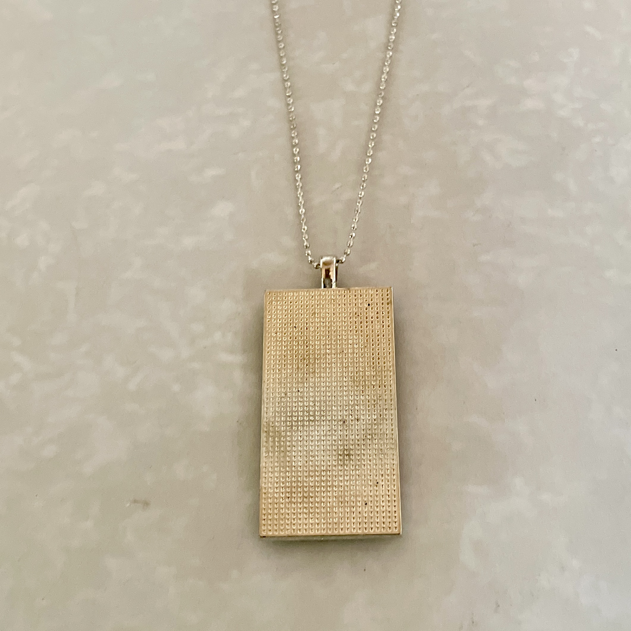 Textured rectangular gold pendant on chain