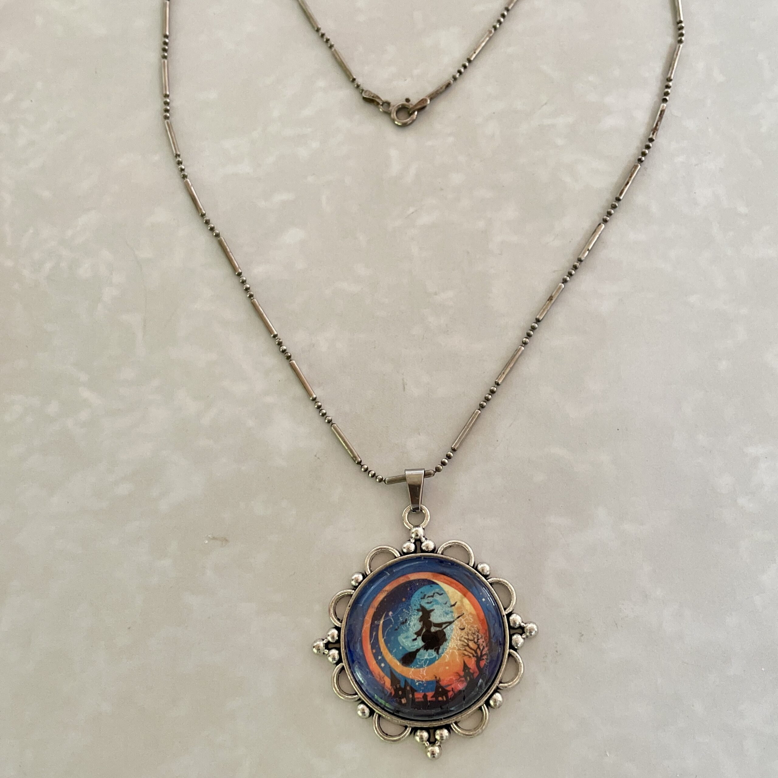 Ornate silver necklace with witch silhouette pendant