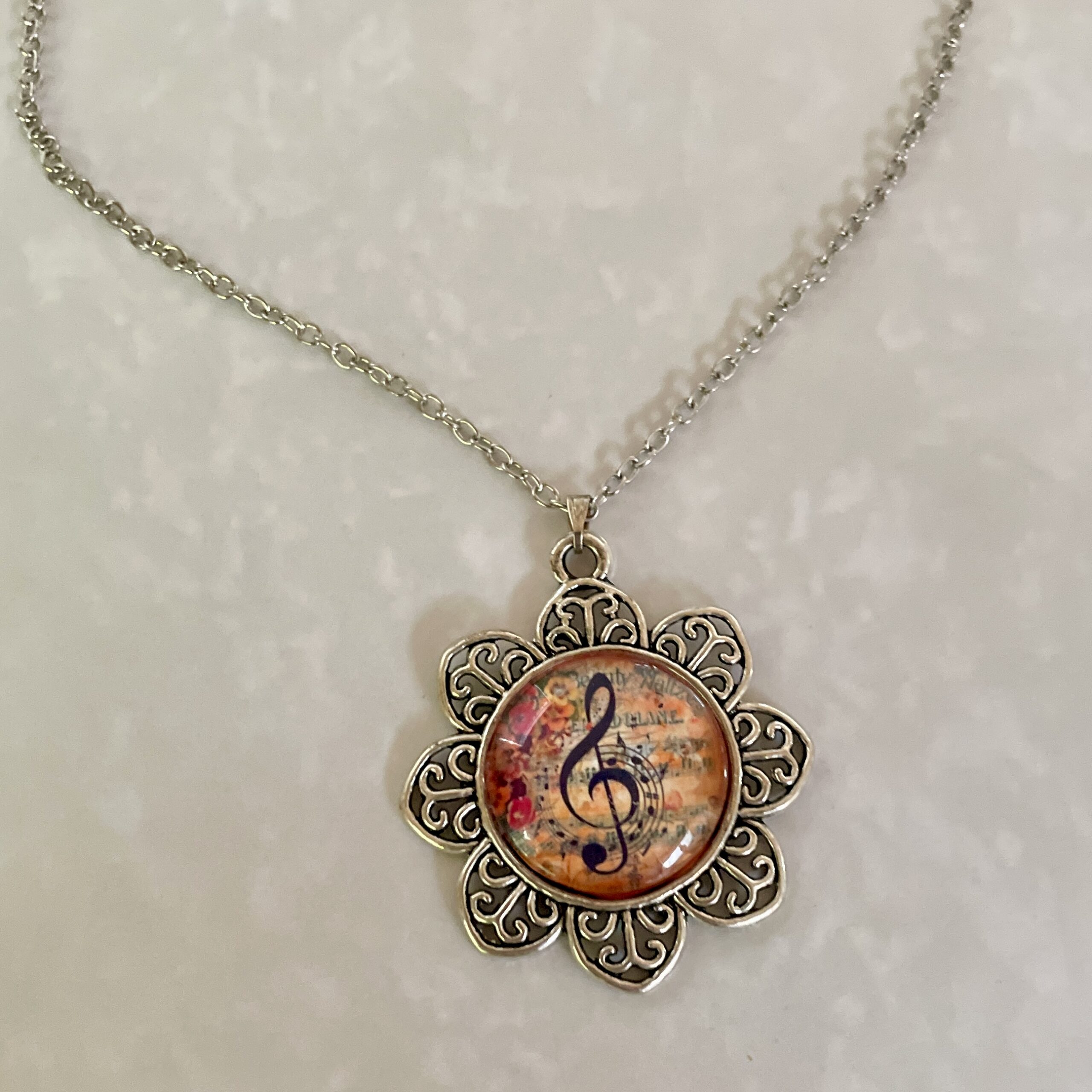 Silver floral pendant necklace with treble clef