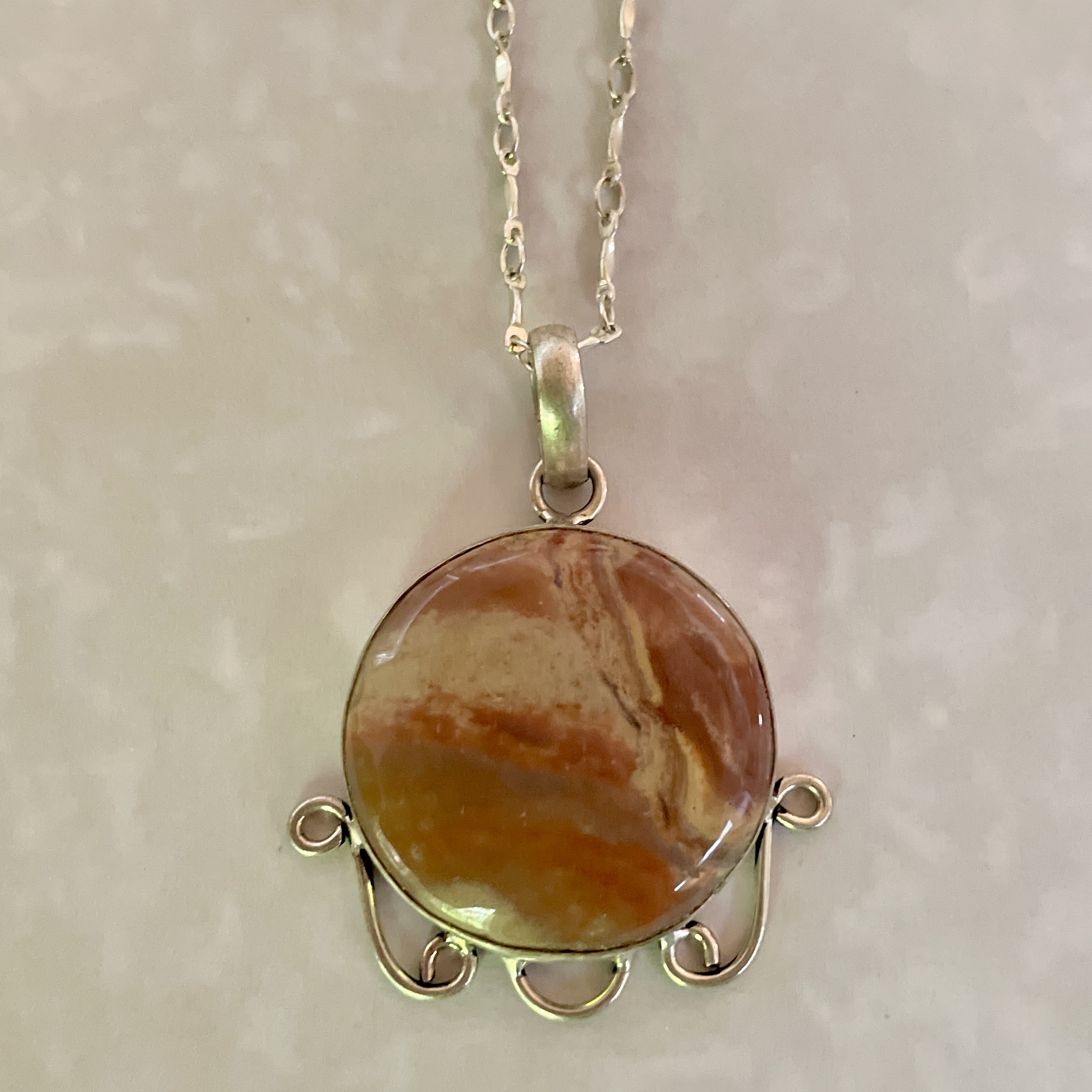 Elegant pendant necklace with marbled orange stone.