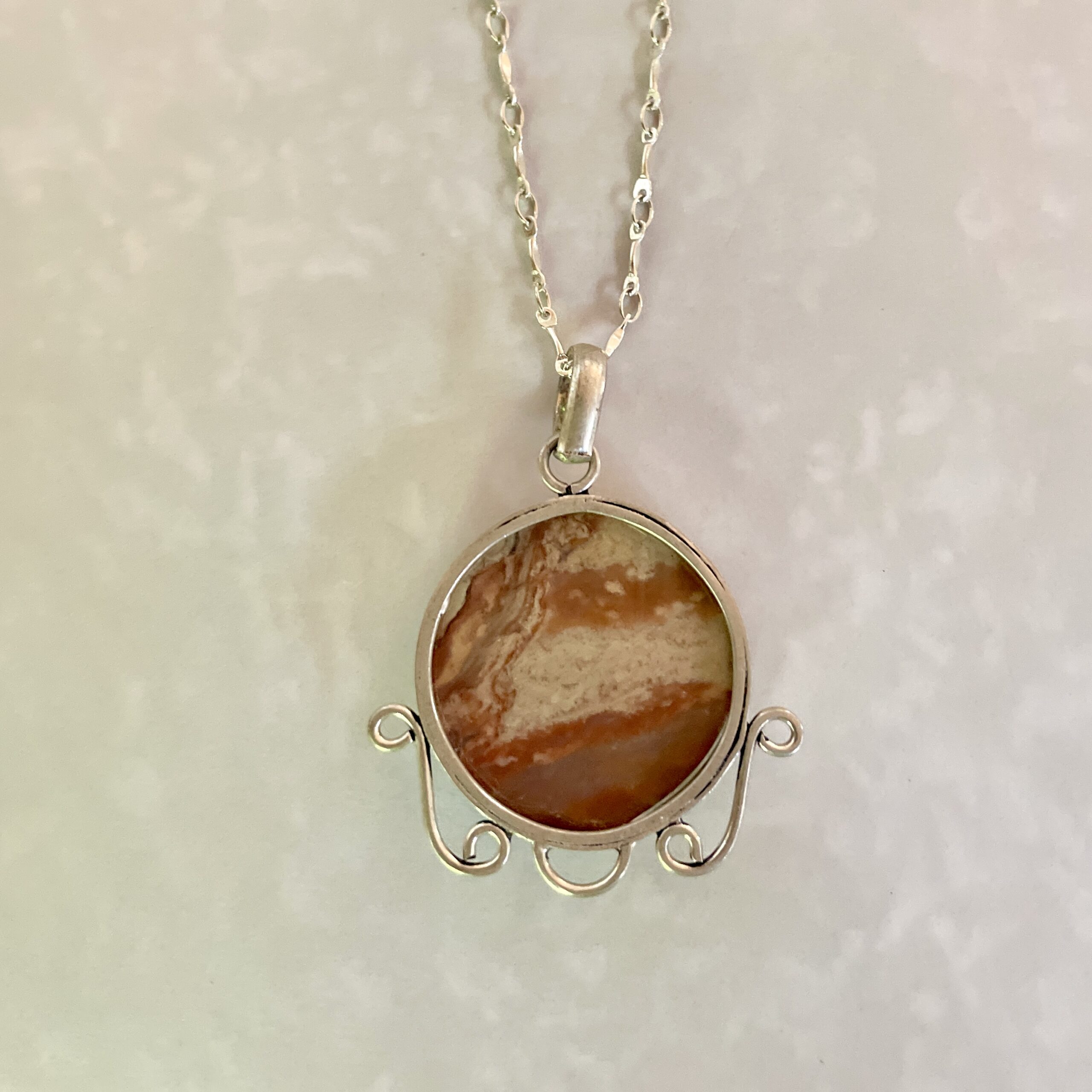 Unique pendant featuring a marbled orange stone.