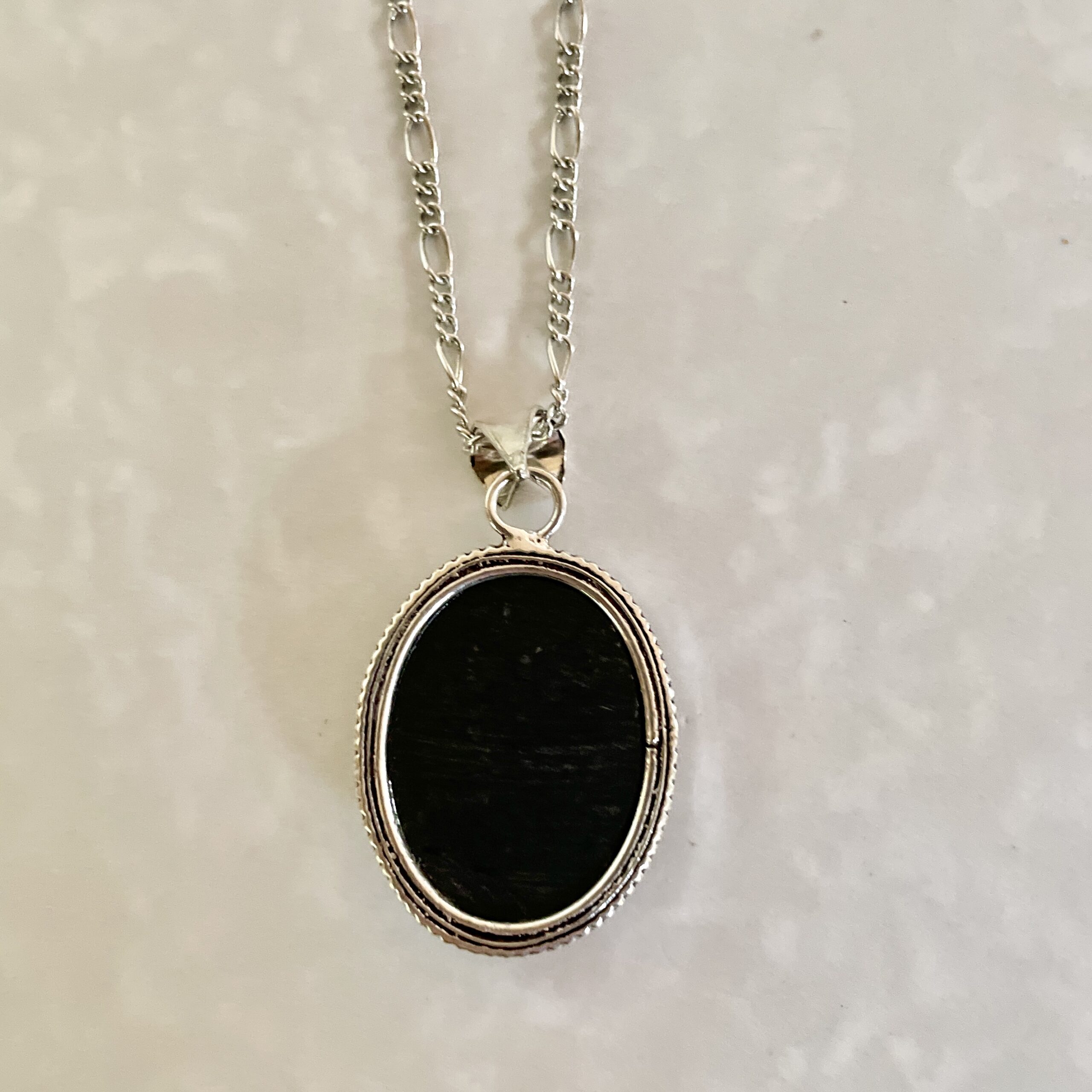 Silver necklace featuring an oval black pendant.