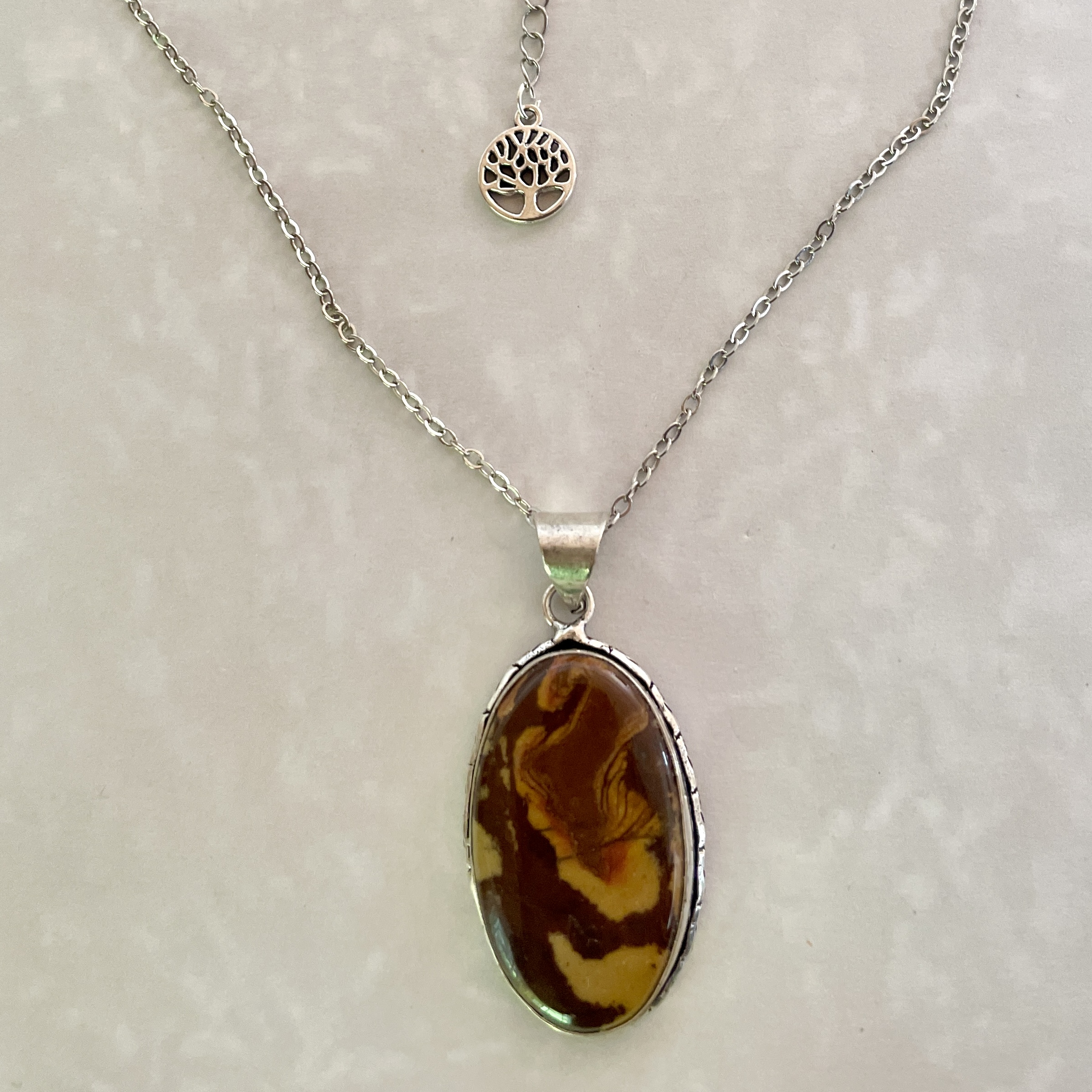 "Silver necklace with marbled brown stone pendant."