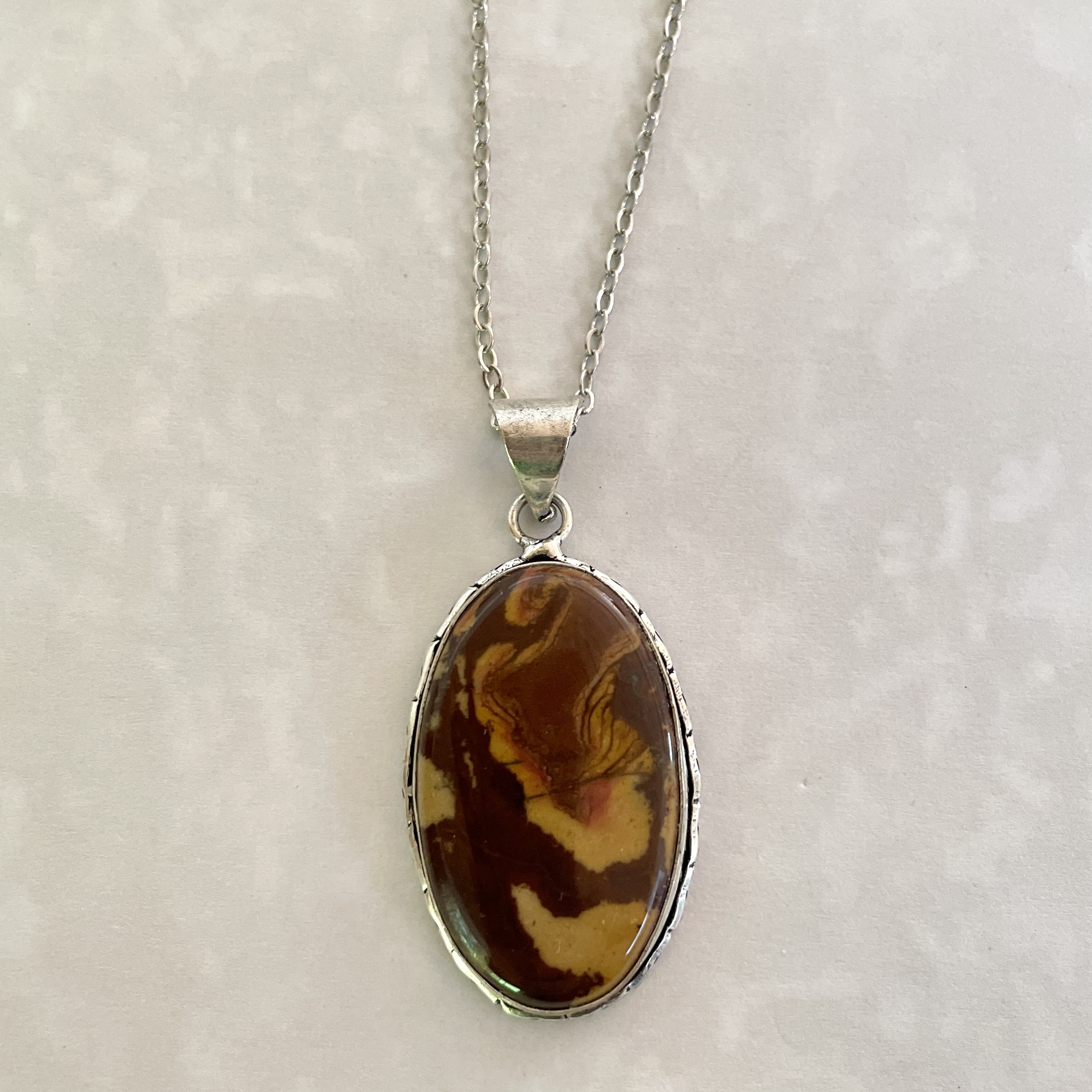 Stylish silver necklace with marbled brown pendant.