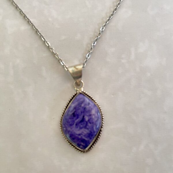 Silver necklace with a vibrant purple pendant.