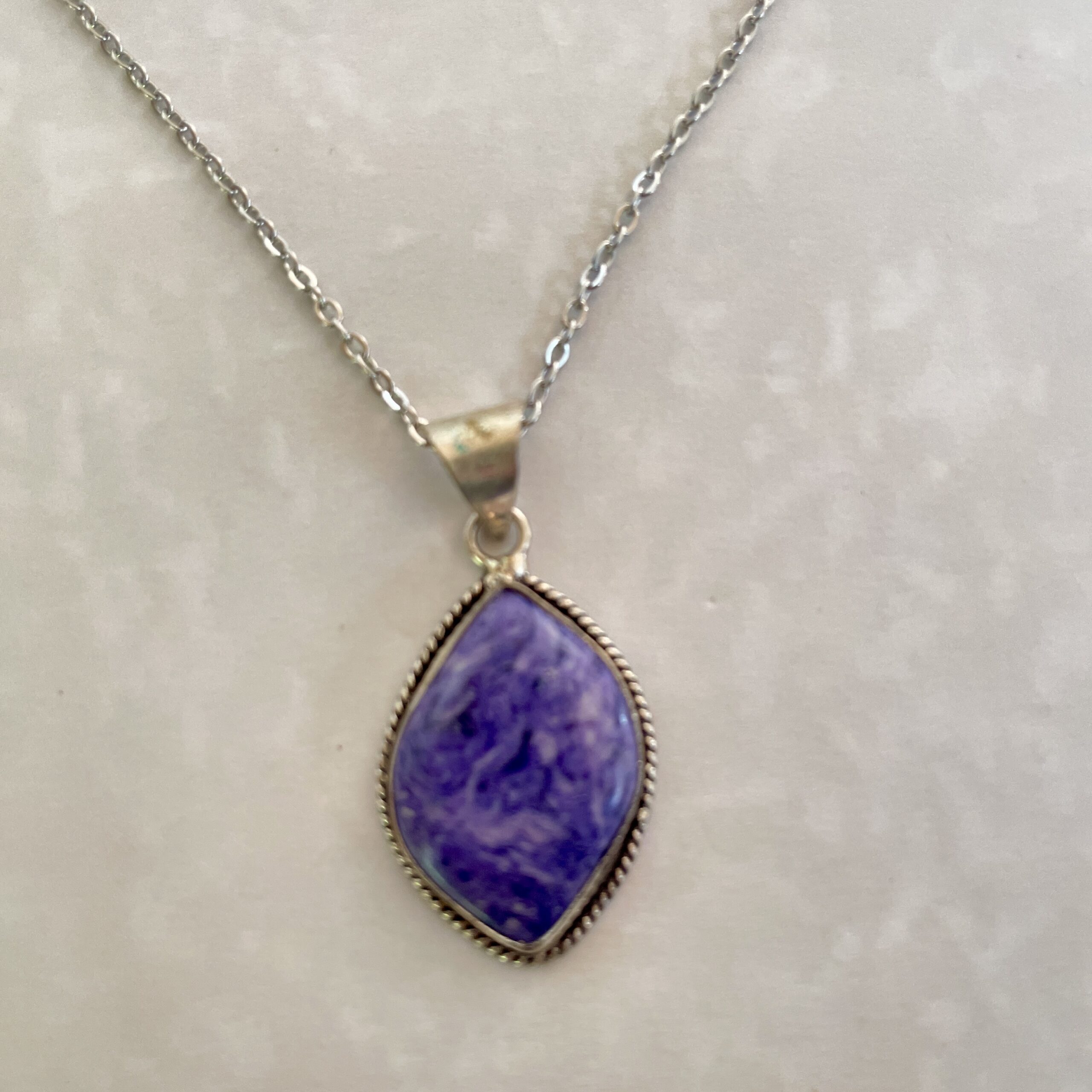 Silver necklace with a vibrant purple pendant.