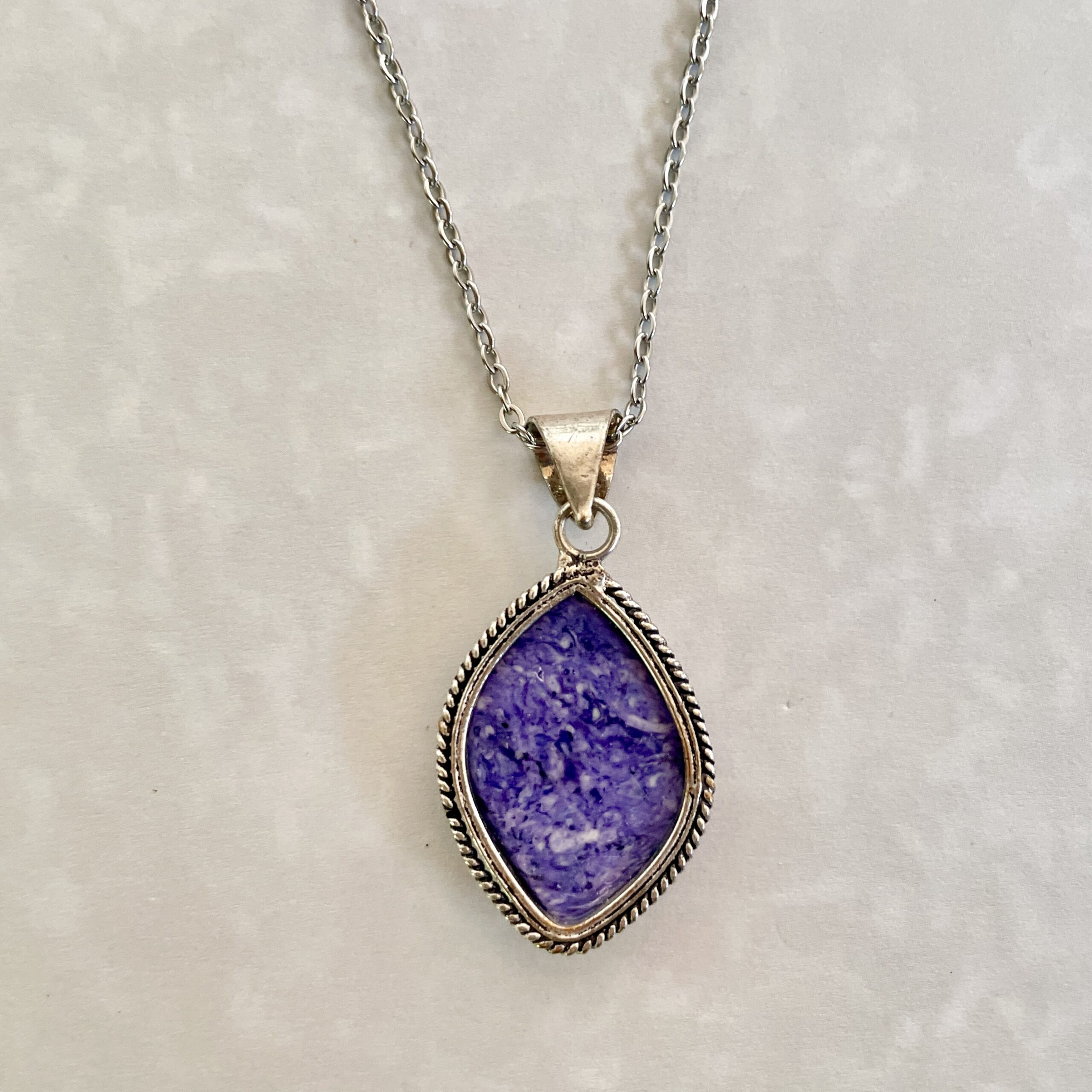 Silver necklace with a purple stone pendant.