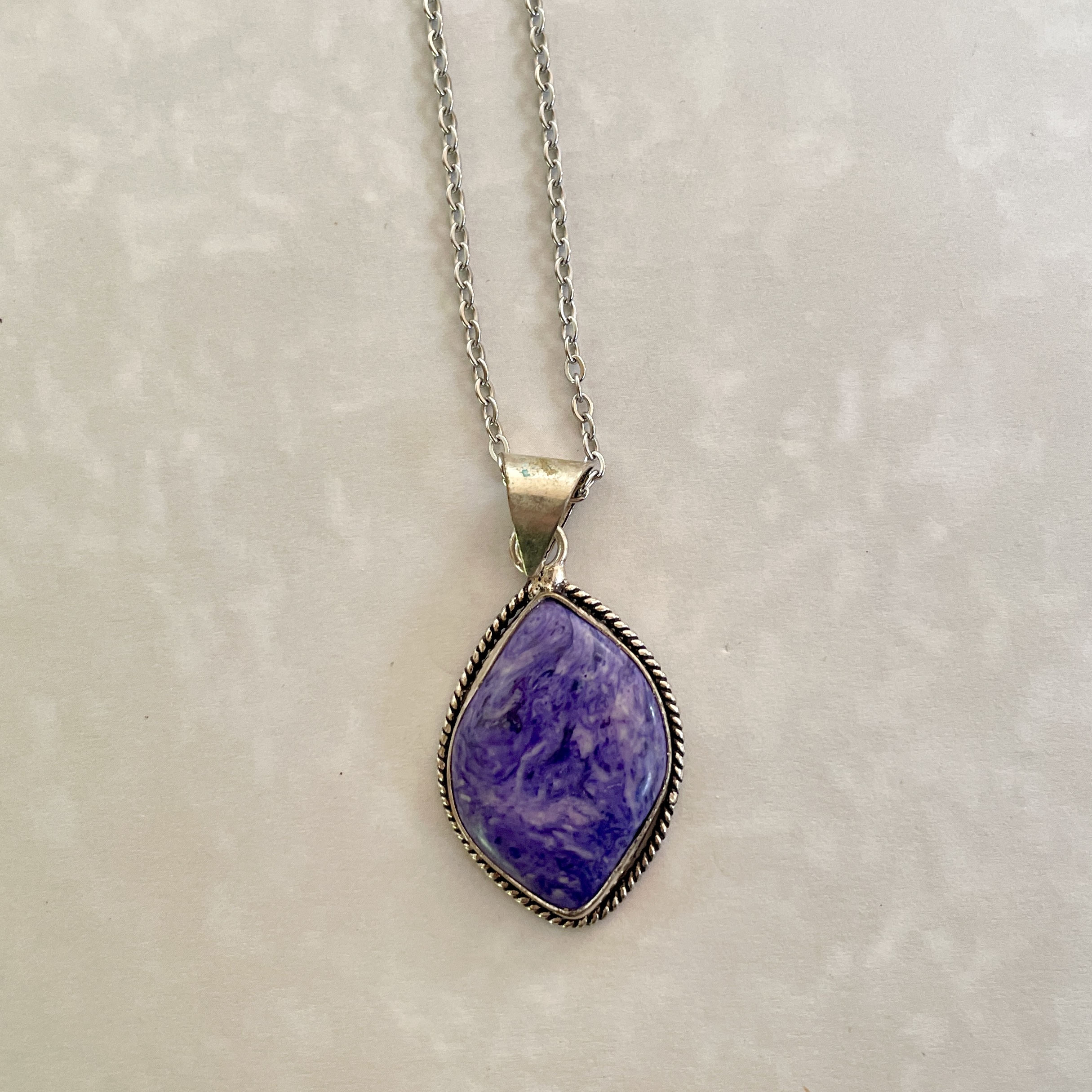 Silver necklace with purple marbled pendant.