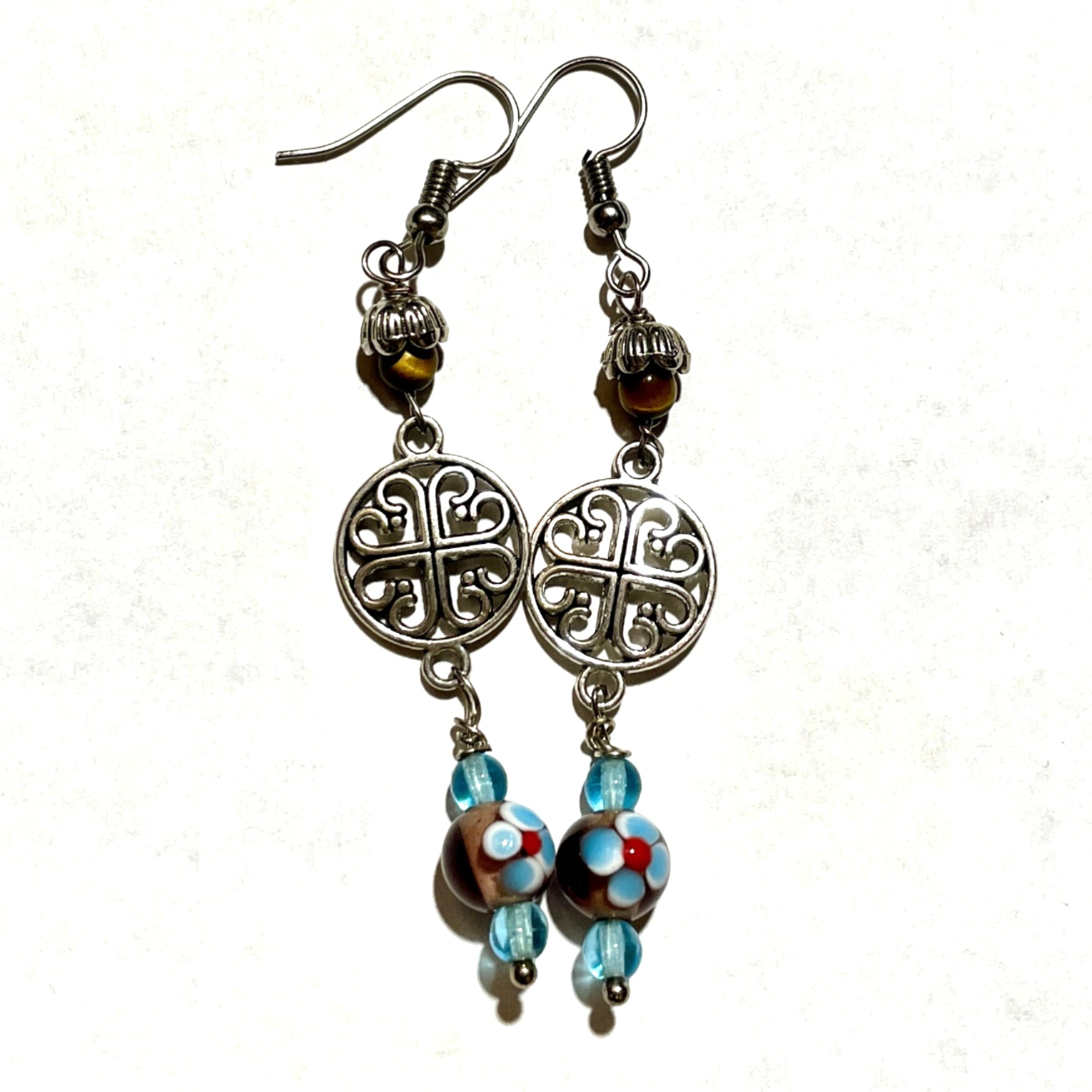 Colorful earrings with intricate silver designs.
