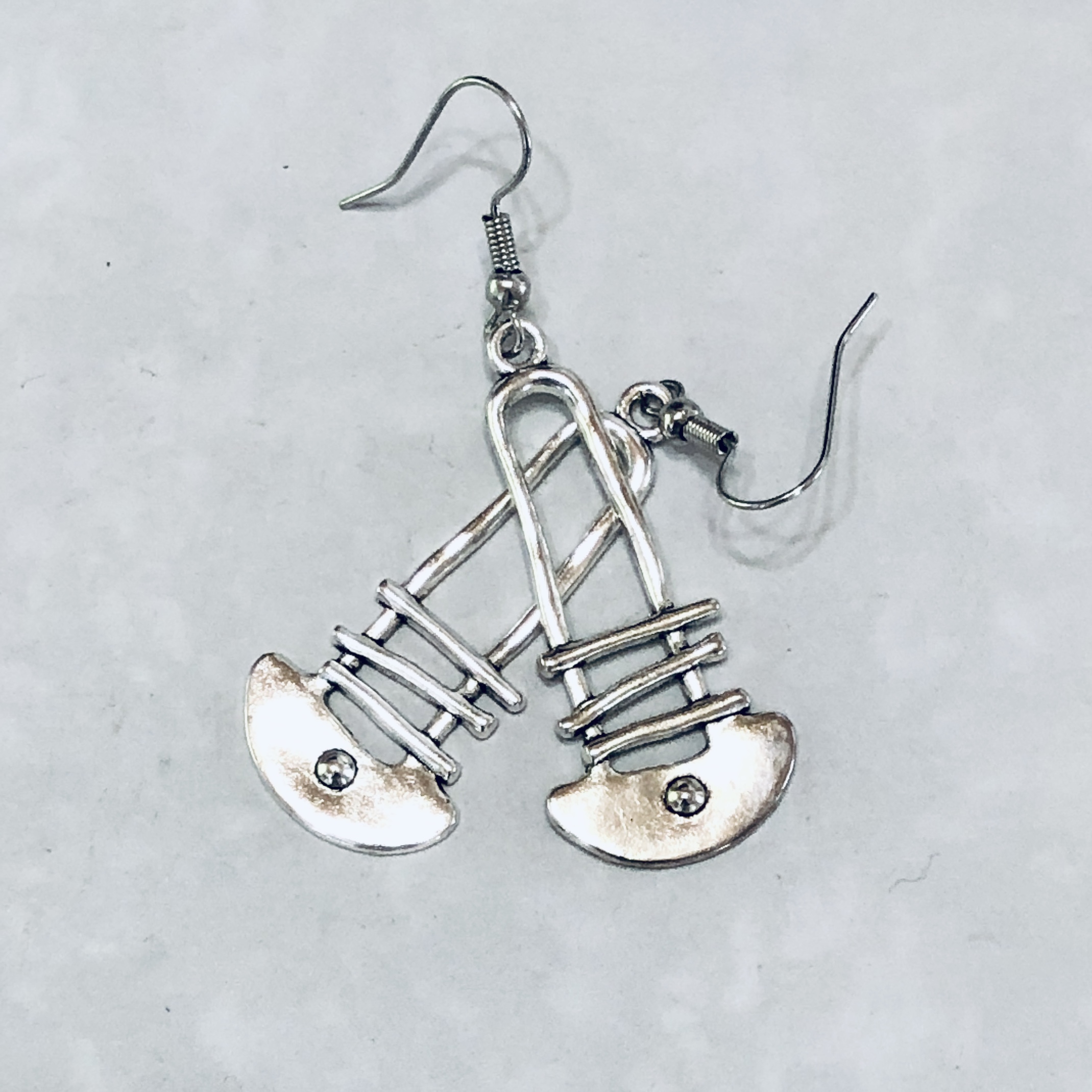 Silver earrings shaped like ballet shoes.